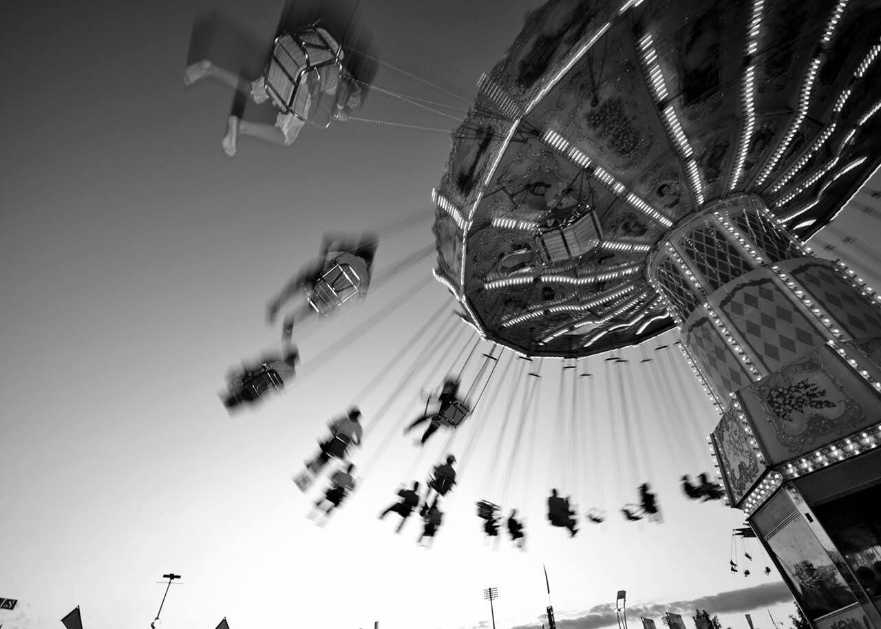 Black and white image of carnival swing ride in motion